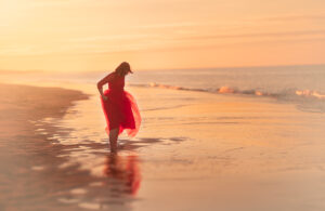 Meisje in rode jurk aan zee zonsondergang